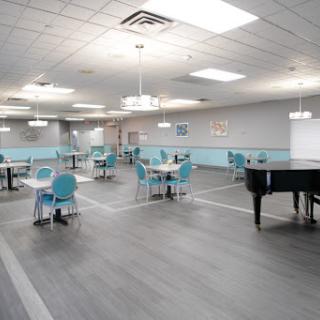 An inviting dining hall featuring modern decor with turquoise accents and a grand piano.