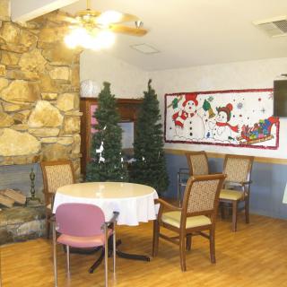 A cozy indoor dining area with a fireplace, table, and chairs, decorated with holiday-themed decorations.