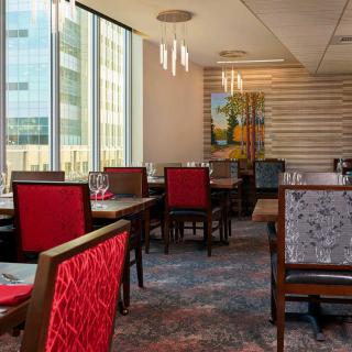 A modern restaurant interior with red chairs and large windows.