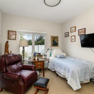 Cozy bedroom with a single bed and armchair, complemented by wall art and a television.