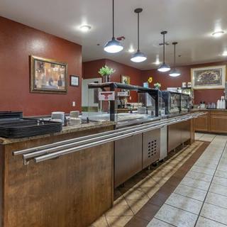 An empty cafeteria buffet with a self-service area and warm lighting.