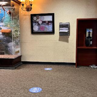 A view of a lobby featuring an aquarium, artwork, and a phone booth with floor markings.