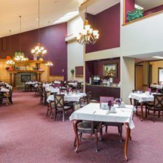A spacious restaurant dining area with elegantly set tables and grand chandeliers.