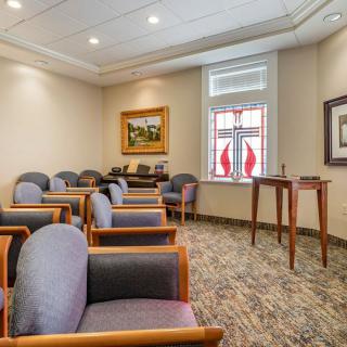 A neatly arranged waiting room with comfortable chairs, artwork on the walls, and a window letting in natural light.