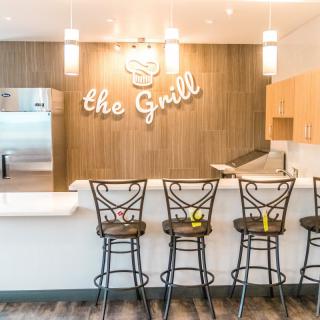 A modern grill restaurant with a sleek bar area and high stools.