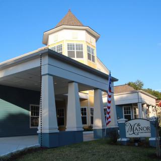 A building with a prominent entrance columns and a sign, featuring a flag on display.