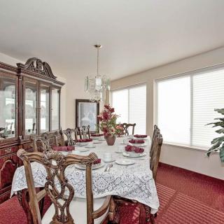 A beautifully set dining room table with ornate chairs and a china cabinet, featuring elegant decor and a plush carpet.
