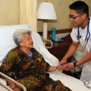 A nurse provides care to an elderly woman in a hospital bed.