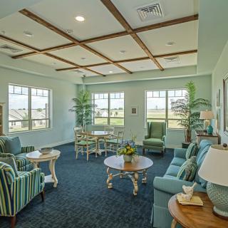 A cozy living room with comfortable seating, tables, and large windows providing ample natural light.