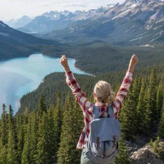 A hiker raises their arms in triumph while overlooking a beautiful mountain lake.