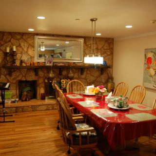A cozy dining room with a decorated table, stone fireplace, and warm lighting.