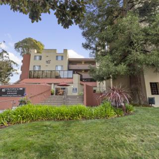 A modern residential building with well-maintained landscaping and tall trees.