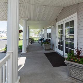 A sunny outdoor porch with seating and decorative plants.