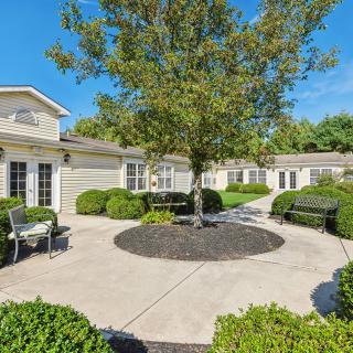 A serene courtyard surrounded by buildings, featuring a tree at the center and benches along the pathway.