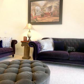 A cozy living room with plush sofas, a tufted ottoman, and elegant decor.