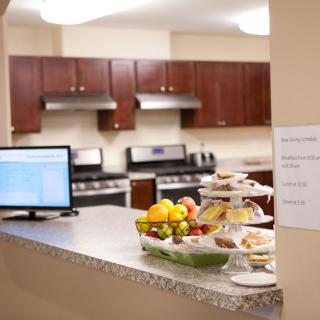 A kitchen with a countertop displaying fruit and pastries, alongside a laptop.