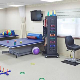 A well-equipped physical therapy and rehabilitation room featuring a treatment bed, exercise equipment, and various therapy tools.