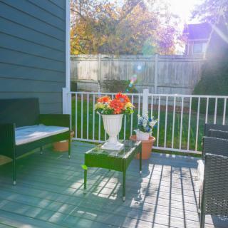 A cozy patio with outdoor seating and a table adorned with vibrant flowers, bathed in warm sunlight.