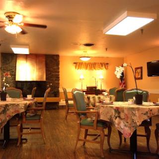 A cozy dining area featuring tables and chairs, illuminated by warm lighting.