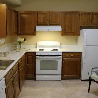 A cozy kitchen with wooden cabinets, featuring a stove, oven, and refrigerator.