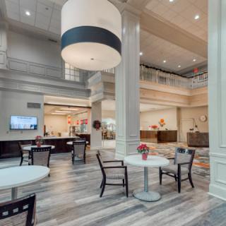 A spacious hotel lobby with modern decor, featuring a seating area and a large chandelier.