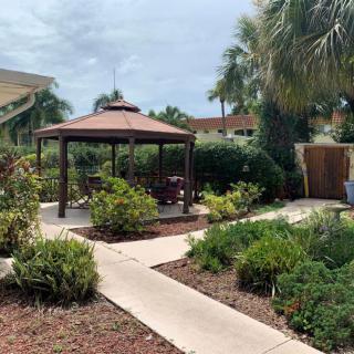 A serene garden featuring a gazebo, surrounded by lush greenery and a winding pathway.