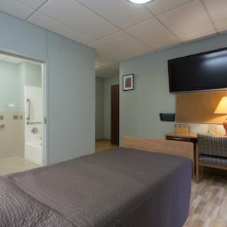 A modern hotel room featuring a queen bed, flat screen TV, and an attached bathroom.