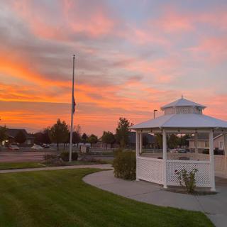 A serene sunset casting vibrant colors over a gazebo in the park.