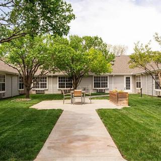 A peaceful courtyard with trees, grass, and benches surrounded by a building.