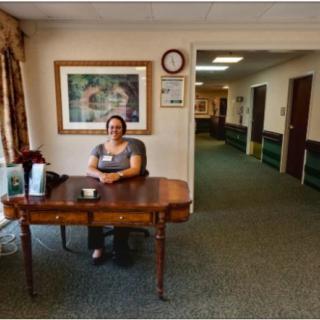 A person sitting at a reception desk in an office hallway.