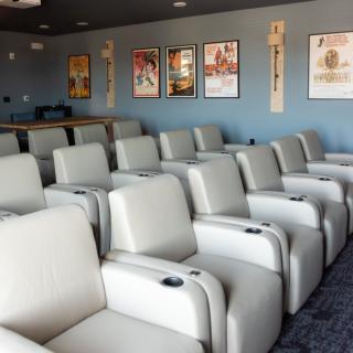 Comfortable recliner seats in a small cinema theater adorned with movie posters.