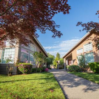 A sunny view of suburban residential buildings with a landscaped garden and pathway.
