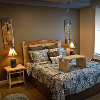 A cozy bedroom with a neatly arranged bed, decorative pillows, bedside tables with lamps, and warm lighting.
