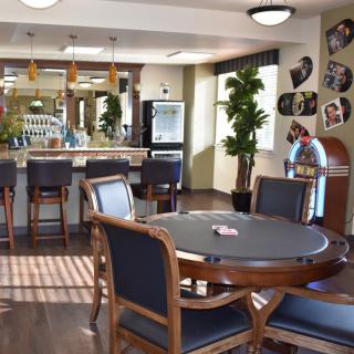 A cozy game room featuring a poker table, bar area, and jukebox with stylish decor.