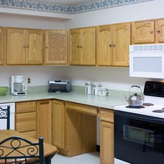 A kitchen with wooden cabinets and various appliances, including a microwave, stove, coffee maker, and toaster.