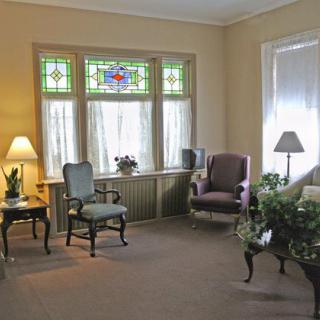 A cozy living room with vintage furniture and a stained glass window.
