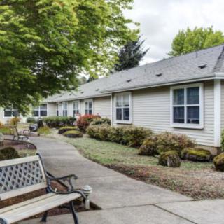 A peaceful residential area with a sidewalk, benches, and well-maintained landscaping.