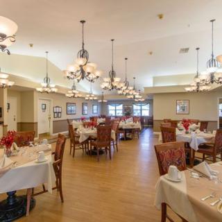 A spacious dining area with neatly arranged tables and chairs, decorated with elegant chandeliers.