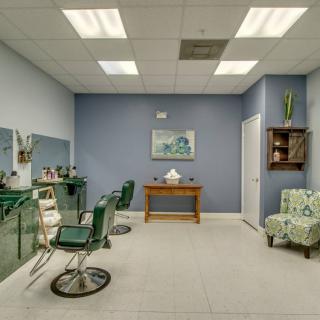 A minimalist salon interior with haircut chairs and a small waiting area.
