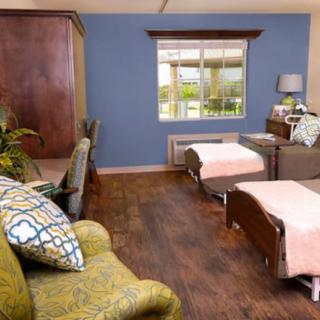 A cozy bedroom with two beds, warm decor, and a large window.