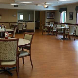 An empty dining area with several tables and chairs arranged on a wooden floor.