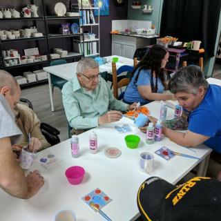 A group of people engaged in a painting and crafts activity at an art class.