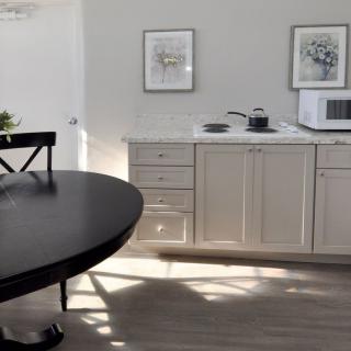 A minimalist kitchen with white cabinets, a microwave, and a black dining table.