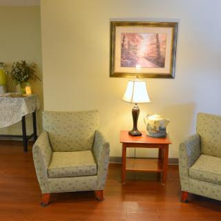 A cozy living room setup with two chairs, a lamp, and artwork on the wall.