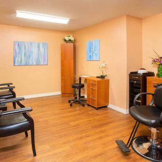 A cozy hair salon interior with chairs and artwork on the walls.