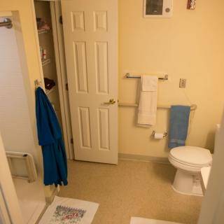 A clean bathroom with towels, a bathrobe, and a shower area.