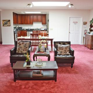 A cozy living room with a red carpet, leather sofas, and an open-plan kitchen.