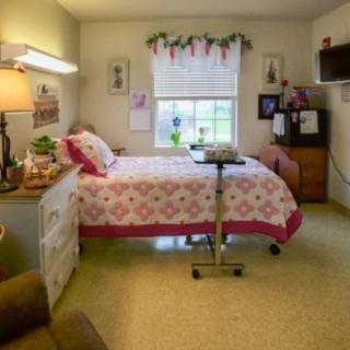 A cozy bedroom with a single bed, floral quilt, and decorative touches.
