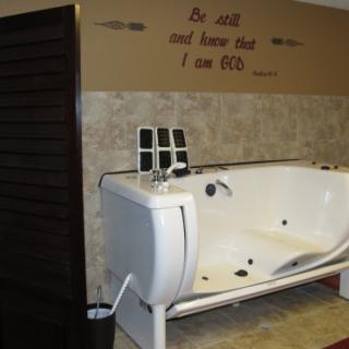 A modern bathroom featuring a jacuzzi tub against a tiled wall with decorative text.