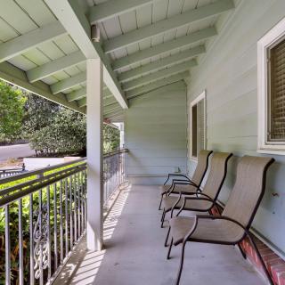 A covered porch with outdoor seating and a railing, providing a comfortable space for relaxation.